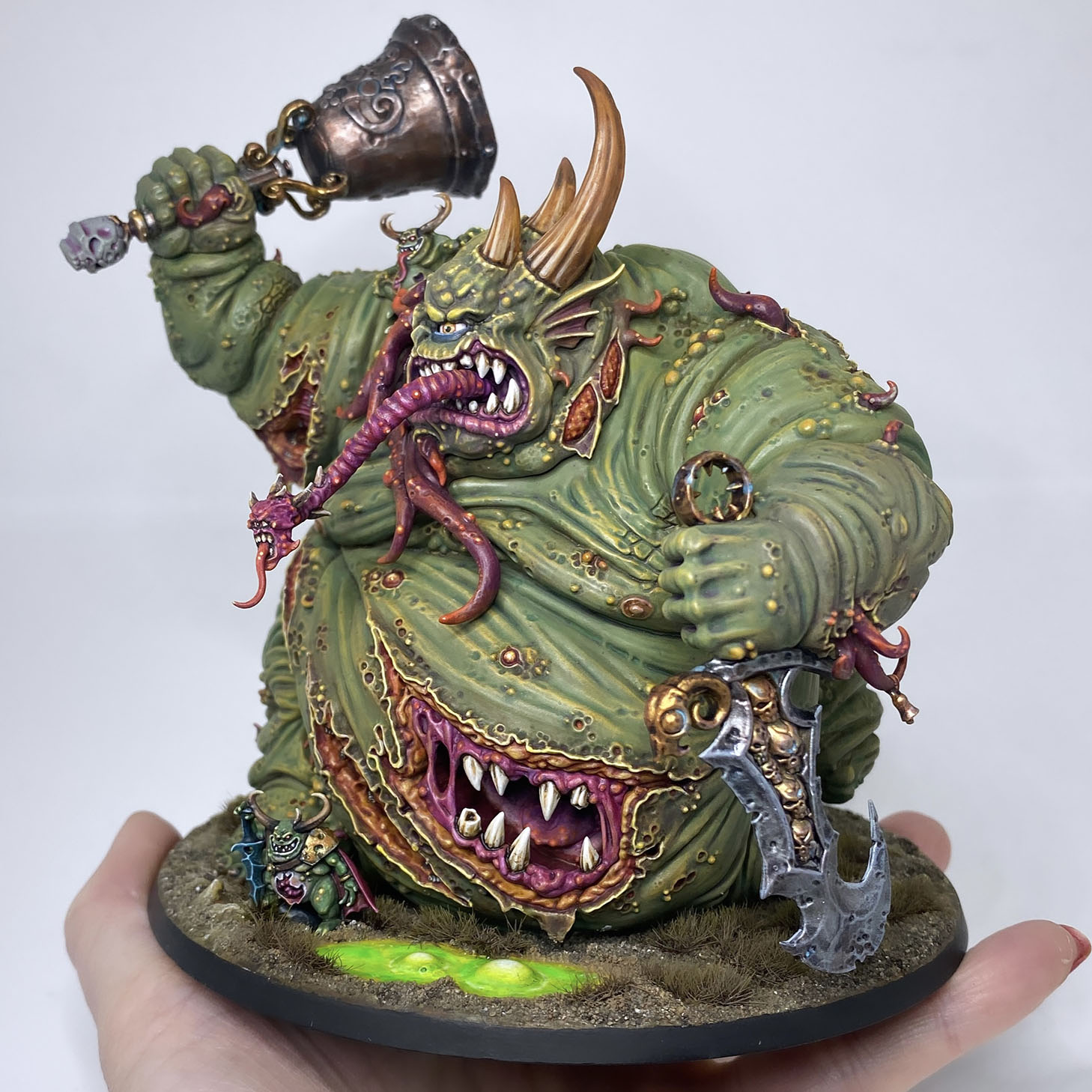 The Great Unclean One / Rotigus is built and painted. There are 3 different distinct builds for AOS and 40K. I have magnetized all the parts of the Great Unclean One and Rotigus. We now have 3 different heads, 3 left arms, 3 right arms and 2 stomach inserts. This way, you can play any variant you want. This is a truly vile model (in the most positive sense of the word!) – it celebrates its corpulence, with rotten, torn flesh slipping aside on its enormous gut to reveal winding intestines within. What an awesome model. Those details are perfectly gruesome. Warhammer - Age of Sigmar and 40K Maggotkin of Nurgle. 👉 Do you want me to build or paint for you? Feel free to contact me. I am excited to hear from you! Height: 13 cm (without weapons) Patching: Green Stuff by citadel_paints Base: custom made with clay Paints: vallejocolors Painted to level: Display Publisher: warhammerofficial Painted by: Debbie Maasdam