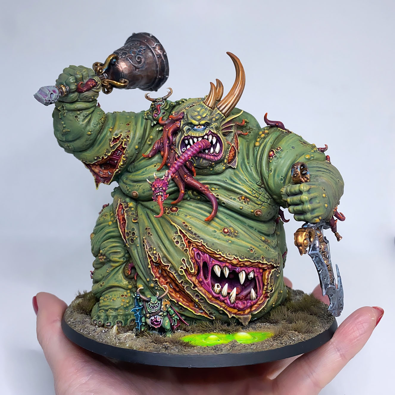 The Great Unclean One / Rotigus is built and painted. There are 3 different distinct builds for AOS and 40K. I have magnetized all the parts of the Great Unclean One and Rotigus. We now have 3 different heads, 3 left arms, 3 right arms and 2 stomach inserts. This way, you can play any variant you want. This is a truly vile model (in the most positive sense of the word!) – it celebrates its corpulence, with rotten, torn flesh slipping aside on its enormous gut to reveal winding intestines within. What an awesome model. Those details are perfectly gruesome. Warhammer - Age of Sigmar and 40K Maggotkin of Nurgle. 👉 Do you want me to build or paint for you? Feel free to contact me. I am excited to hear from you! Height: 13 cm (without weapons) Patching: Green Stuff by citadel_paints Base: custom made with clay Paints: vallejocolors Painted to level: Display Publisher: warhammerofficial Painted by: Debbie Maasdam